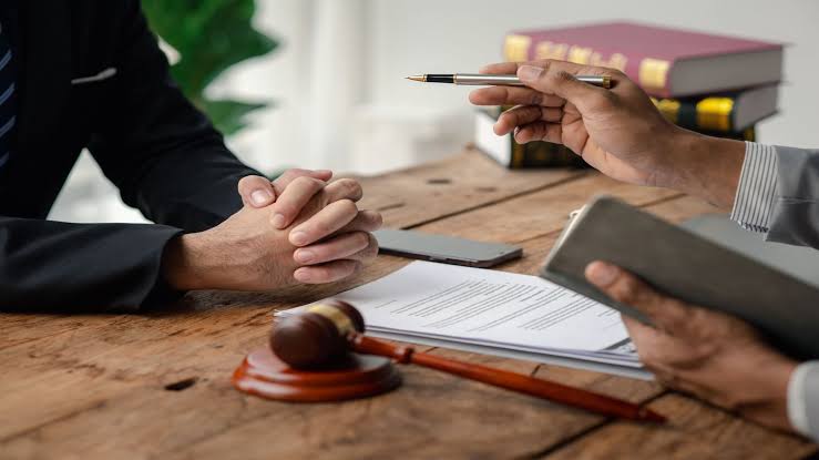 A legal consultation taking place across a wooden desk with a gavel and documents, where an experienced amputation injury lawyer reviews a case with a client.